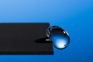 Professor Chunlei Guo has developed a technique that uses lasers to render materials hydrophobic, illustrated in this image of a water droplet bouncing off a treated sample.Photo: J. Adam Fenster / University of Rochester